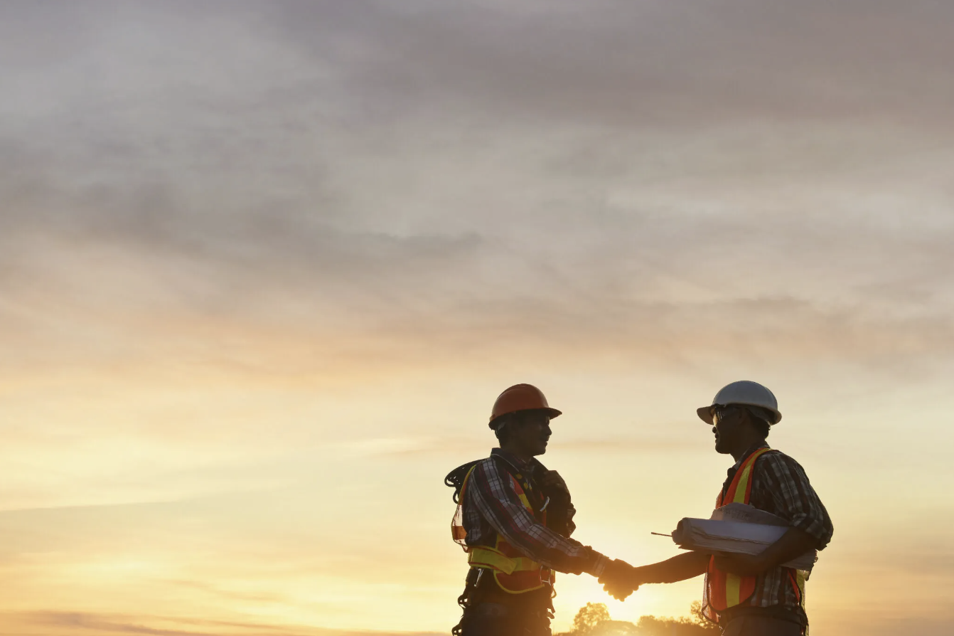 Two construction professionals shaking hands at sunset – zumBrunnen